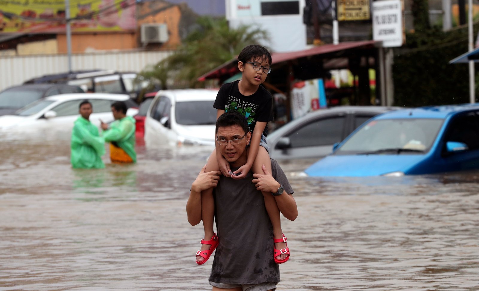 Seorang Ayah sedang menggendong Anaknya dalam menerjang Banjir